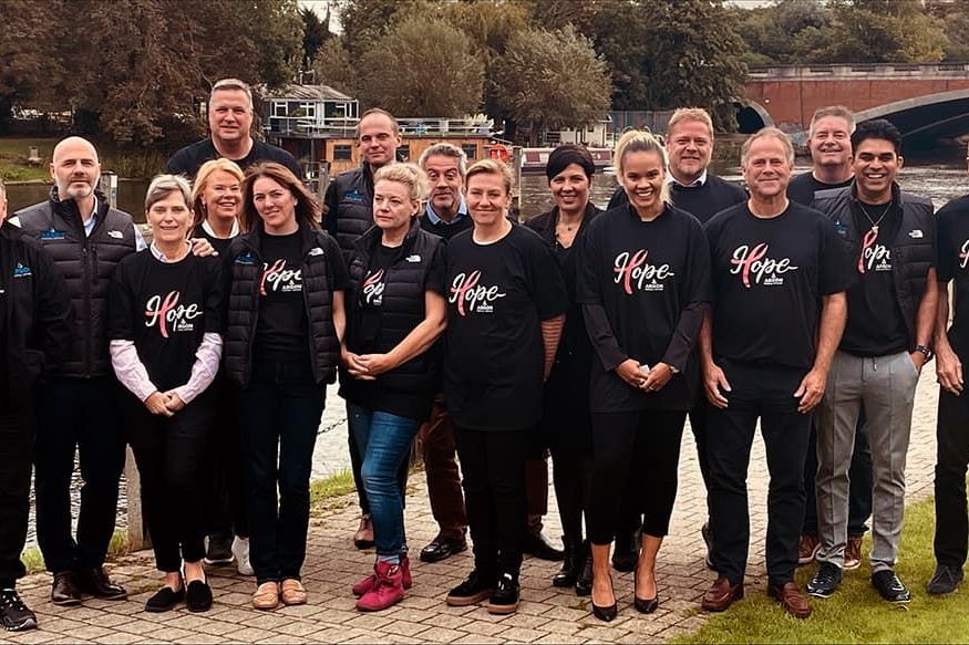 group of employees posing together in breast cancer hope shirts